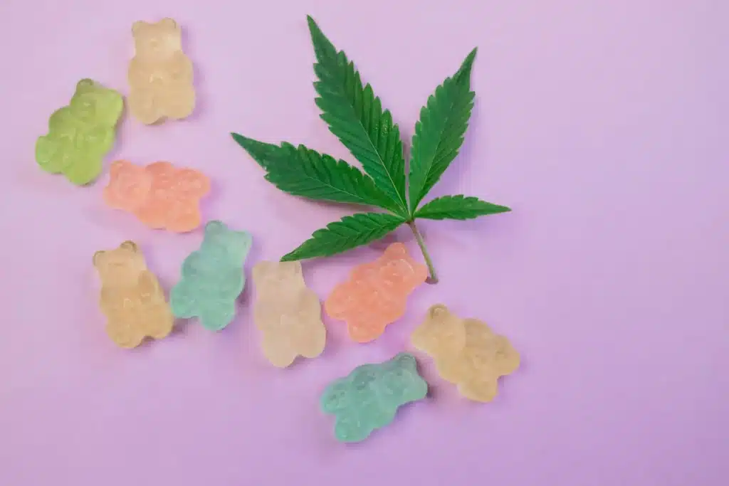 Gummibärchen liegen neben einem Cannabisblatt